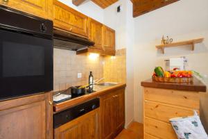 a kitchen with wooden cabinets and a sink and a television at Chalet Résidence Chantey Mourry 6 - Happy Rentals in Argentiere