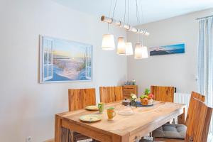 a dining room with a wooden table and chairs at Darßwaldradler in Wieck