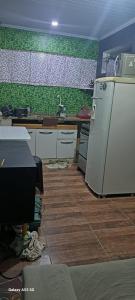 a kitchen with a white refrigerator and a green wall at Fundilhos House in Rio das Ostras
