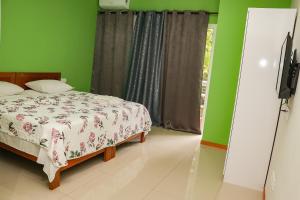 ein Schlafzimmer mit einem Bett und einer grünen Wand in der Unterkunft Residencial Chez Flávia in Pombas + 4 Fotos