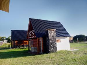 a small cabin with a black roof and a stone pillar at Entre aromos y lavandas in San Clemente del Tuyú