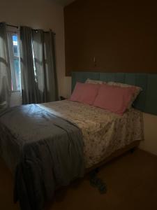 a bedroom with a bed with pink pillows and a window at A casa do Breno in São José da Coroa Grande