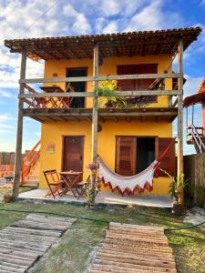 a yellow house with a hammock in front of it at Chalés Calica in Caraíva
