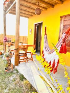 a yellow house with a hammock on a patio at Chalés Calica in Caraíva