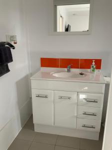 a bathroom with a white sink and a mirror at Jetty Rd Granny Flat in Normanville