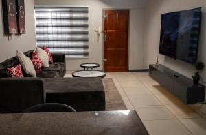 a living room with a couch and a flat screen tv at Home Very Close To CBD in Gaborone