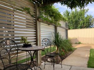 a patio with two chairs and a table and a fence at Jetty Rd Granny Flat in Normanville