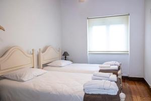 2 letti in una camera da letto con lenzuola e asciugamani bianchi di Quinta das Maçãs by SH ad Alvaiázere Altre 40 foto