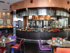 een restaurant met tafels en stoelen en een keuken bij Novotel Barcelona City in Barcelona