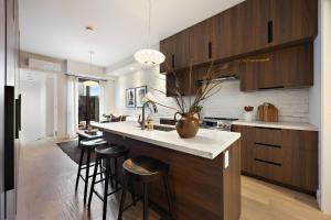 a kitchen with wooden cabinets and a counter with bar stools at The Brick Hotel - The Second Suite in Toronto