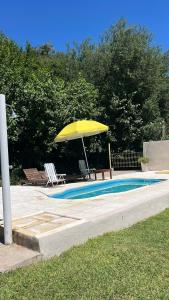 a yellow umbrella and chairs next to a swimming pool at Quinta Atardeceres in Aldea Brasilera