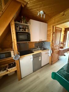 a kitchen with white cabinets and appliances in a cabin at Duplex cosy jusqu'à 6 personnes- chalet des Pléiades - départ skis aux pieds en bordure de piste sans portage - au milieu des fleurs en été - l'autre duplex du chalet est également à nous in Risoul
