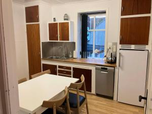 a kitchen with a table and a white refrigerator at Spacious 3-Bedroom Apartment with Comfy Beds in Central Vágur, Island of Suðuroy in Vágur