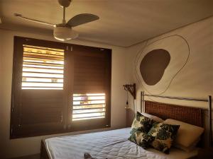 een slaapkamer met een bed, een plafondventilator en een raam bij Casa Dendê Praia do Forte in Praia do Forte