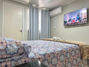a bedroom with a bed and a tv on the wall at Suíte Quarto 3km de Florianópolis in São José