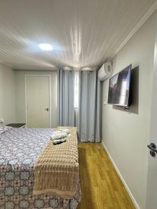 a bedroom with a bed and a flat screen tv at Suíte Quarto 3km de Florianópolis in São José +19 photos