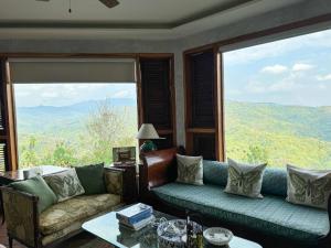 a living room with a couch and a large window at The Chaisai Private Lodge in Ban Huai San Mai