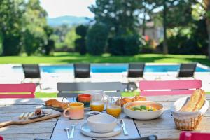 a wooden table with breakfast food on it at La Maison et l'Orangerie in Saint-Jean-des-Vignes
