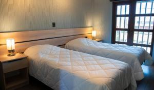 a hotel room with two beds and two windows at Hotel Laraquete in Laraquete