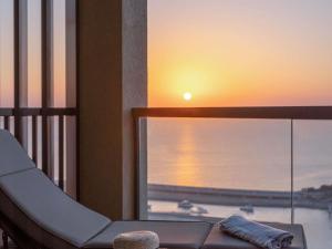 uitzicht op een zonsondergang vanaf een balkon met een stoel bij Sofitel Dubai Jumeirah Beach in Dubai
