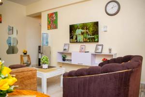 ein Wohnzimmer mit 2 Sofas und einem TV an der Wand in der Unterkunft Bamburi BnB in Mombasa