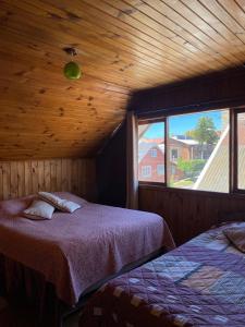 a bedroom with two beds and a large window at Hostal Casa Damasco in Ancud