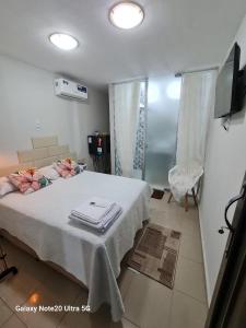 a bedroom with a bed with a white blanket and a television at THEHotelBoutiqueCidadeVelha in Belém
