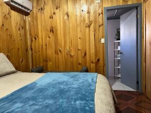 een slaapkamer met een bed en een houten wand bij Cabañas Valentina in Valdivia