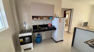 a kitchen with a white refrigerator and a stove at Flat em Carapibus in Conde +1 photo
