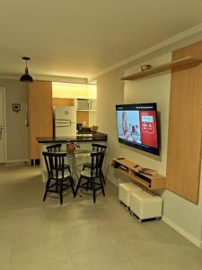 a living room with a table and a tv on a wall at Apartamento novo entre a praia dos Ingleses e Santinho in Florianópolis