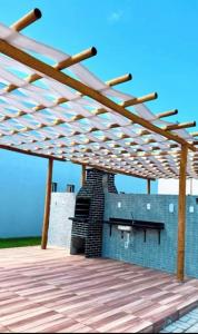 a wooden pergola on a deck with a fireplace at NG Flat seu refúgio do mar in João Pessoa