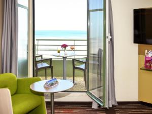 een kamer met een balkon met een tafel en een bank bij Mercure Granville Le Grand Large in Granville