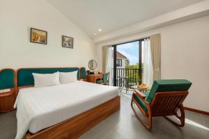 a bedroom with a bed and a chair and a window at Gia Huy Riverside Hotel Hoi An in Hoi An