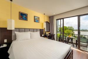 a bedroom with a large bed and a balcony at Gia Huy Riverside Hotel Hoi An in Hoi An