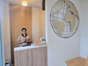 una donna in piedi al bancone con un mappamondo sul muro di S.P.C Apartment by Brodderud a Bangkok