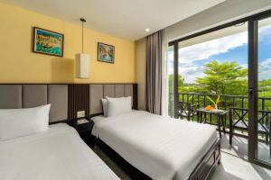 two beds in a room with a balcony at Gia Huy Riverside Hotel Hoi An in Hoi An +80 photos