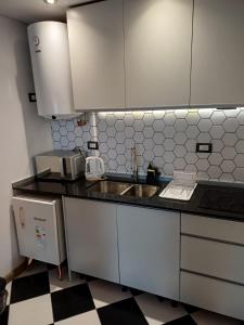 una cucina con mobili bianchi e un lavandino di Garden Block Departamentos Temporarios a San Luis