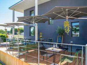 een restaurant met tafels en parasols op een terras bij ibis Styles Pertuis Portes du Luberon in Pertuis