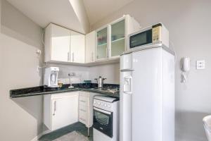 een kleine keuken met witte kasten en een koelkast bij Lindo Vista Mar, Praia do Buracão - Rio Vermelho in Salvador