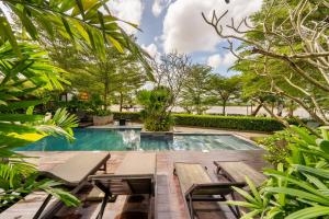 a pool with benches and a fountain in a garden at Gia Huy Riverside Hotel Hoi An in Hoi An