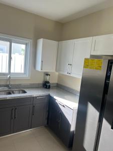 a kitchen with white cabinets and a stainless steel refrigerator at Gate home by ocean point in Lucea