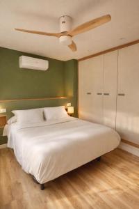 een slaapkamer met een groot bed met een plafondventilator bij El Ático in Gandía +10 foto's