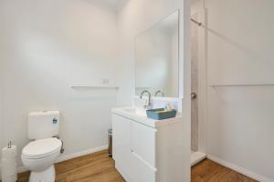 a white bathroom with a toilet and a shower at Wheeler's Paradise in Paradise Beach +15 photos