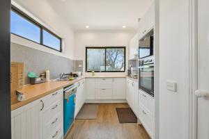 a kitchen with white cabinets and a window at Wheeler's Paradise in Paradise Beach