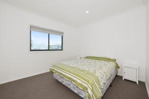 a white bedroom with a bed and a window at Wheeler's Paradise in Paradise Beach