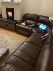 een bruine leren bank in een woonkamer met een laptop bij Riverchapel Guesthouse in Courtown