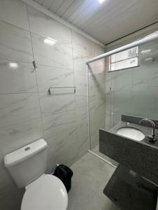 a bathroom with a white toilet and a sink at Quarto Suíte Na grande Florianopolis in São José