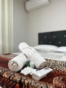 a pile of towels and a remote control on a bed at Quarto Suíte Na grande Florianopolis in São José