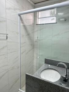 a bathroom with a sink and a glass shower at Quarto Suíte Na grande Florianopolis in São José