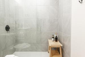 a white bathroom with a shower and a wooden stool at Bradshaw Lofts The Brixton King Suite in Stratford +33 photos